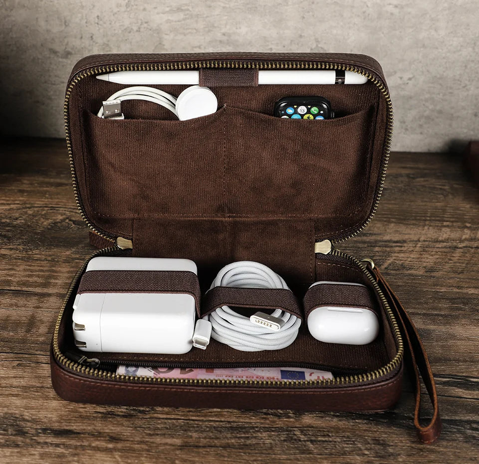 Brown travel case with electronic accessories on a wooden surface