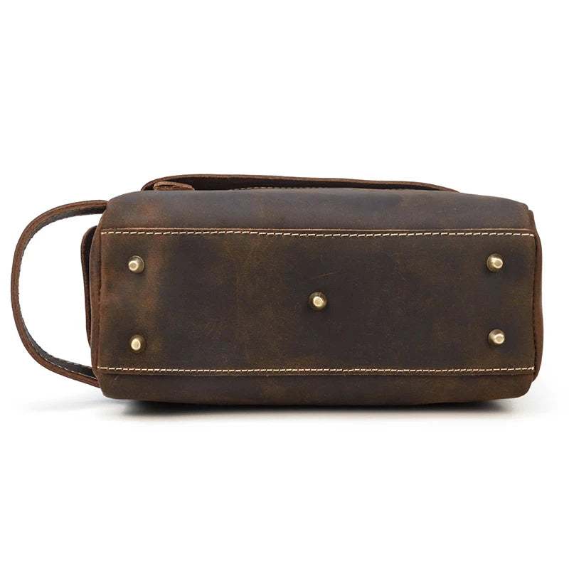 Brown leather toiletry bag with gold studs on a white background