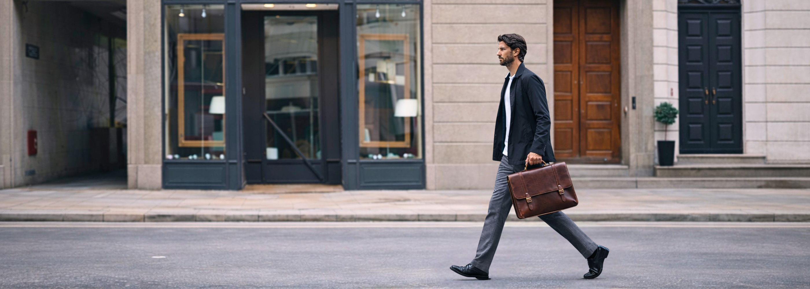 Man walking in the city carrying a leather briefcase, suited for work and everyday commuting.